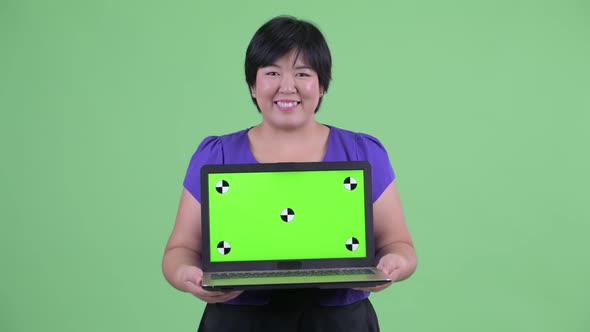Happy Young Overweight Asian Woman Thinking While Showing Laptop