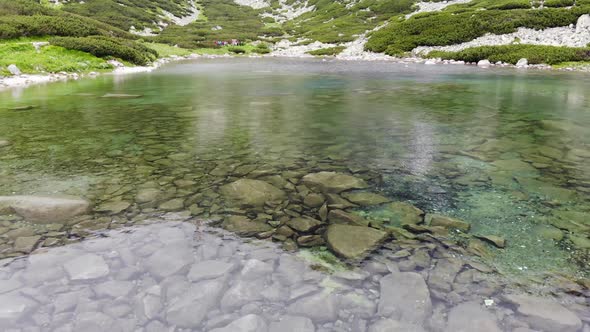 Flying Backwards Low over Crystal Clear Mountain Lake in Slovakia