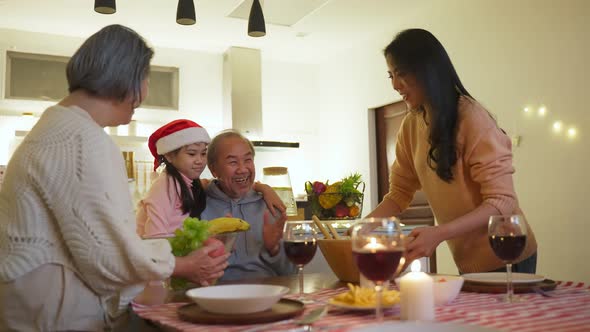 Asian happy family having Christmas holiday party and eat foods together on dinner table in house.