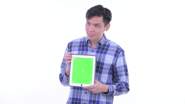 Happy Young Asian Hipster Man Thinking While Showing Digital Tablet