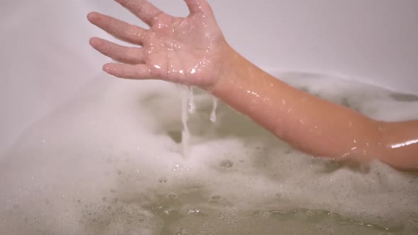 Boy Hand in Soapy Foam Plays with Water in Bathroom