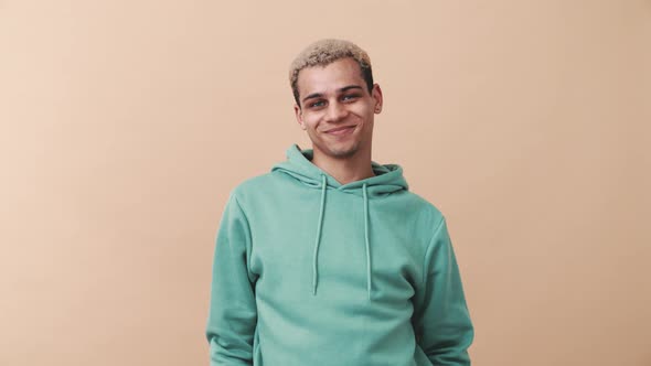 Happy curly-haired man wearing blue hoodie looking at the camera