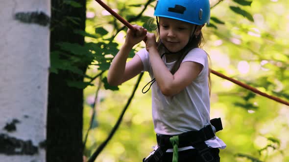 Extreme Rope Adventure in the Park - a Little Girl Moving Over the Rope Bridge in Full Insurance