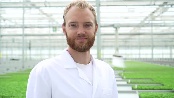 Hydroponic Greenhouse View of Young Man Posing for Camera and Smiling at Modern Farm Spbd