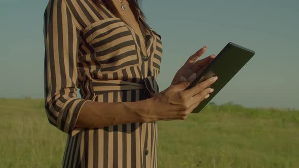 Closeup of Black Female Hands Networking Online on Tablet Pc on Field