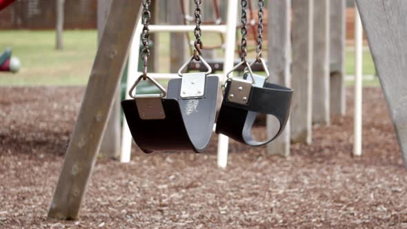 Empty swing set in an empty playground. Swings blowing in the wind.