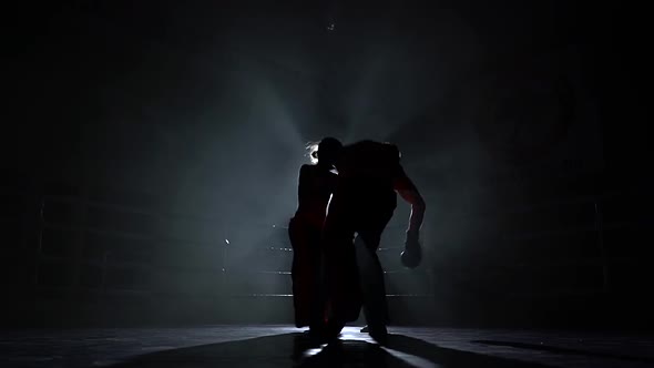 Men with a Girl Beating in the Ring in the Dark. Silhouette