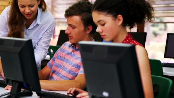 Teacher assisting students in computer class