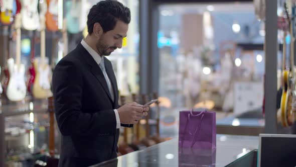 Young handsome man using smartwatch to payment contactless on counter 