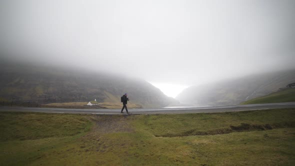 Hiker On Empty Misty Road On Faroe Islands