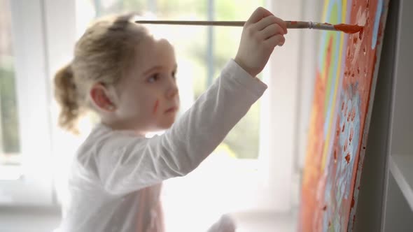 Little girl painting picture with paintbrush