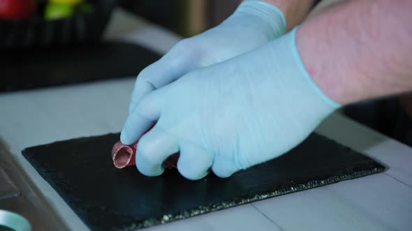 Cook in Gloves Spreads Sliced Jamon or Meat on Black Plate in Restaurant Kitchen, Food