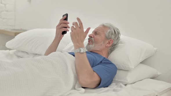 Angry Old Man Yelling on Phone Lying in Bed