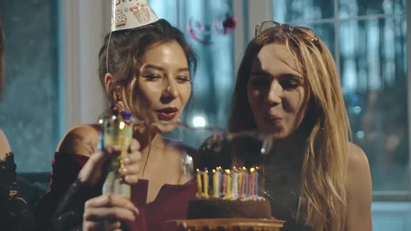 Close Up Portrait of Young Multiracial Female Friends Blowing Out Candles on Birthday Cake and