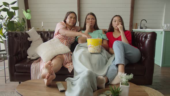 Multiracial Women Expressing Fright By Scary Scene of Film Indoors