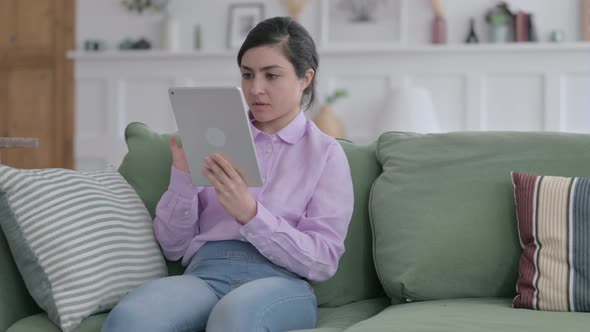 Indian Woman having Loss on Tablet on Sofa