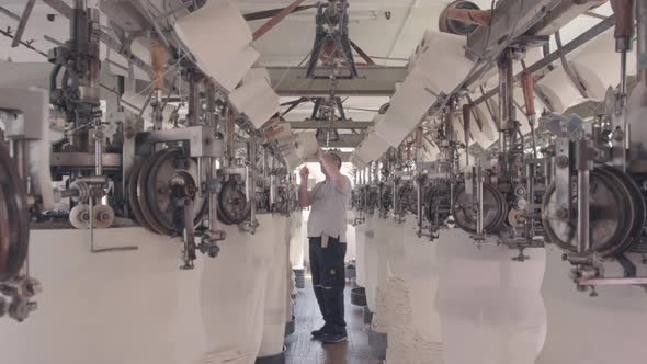 Workers working at a circular knitting machine in knitting factory