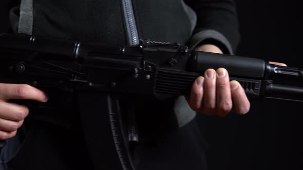 A Bandit Stands with a Gun in Hand on a Black Background. Close-up Panorama From Left To Right