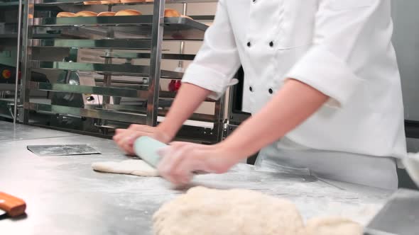 Chef is preparing pastry dough, baking bakery food on a stainless steel table.