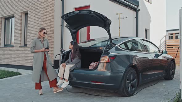 Woman and Girl Waiting for Electric Car to Charge