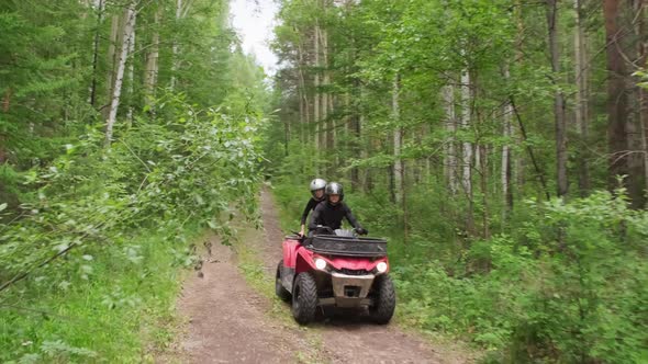 Couple in Helmets Driving Quad Bike in Forest