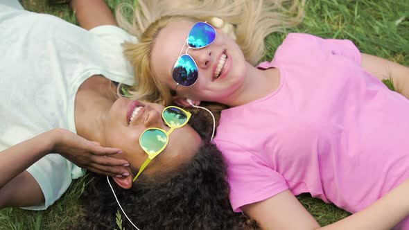 Summer Vacation, Young Women Lying on Grass and Listening to Music on Smartphone