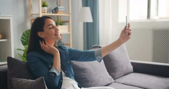 Pretty Young Lady Posing for Smartphone Camera Taking Selfie in Apartment