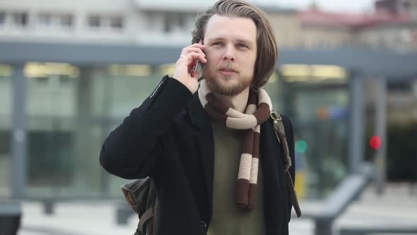 stylish guy in scarf and coat talking by mobile phone at street of Wroclaw, Poland