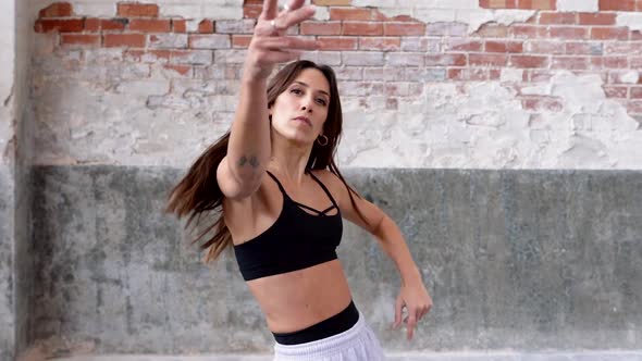 Female hip-hop dancer performing in front of flaking wall