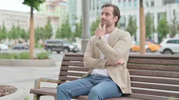 Pensive Young Man Thinking While Sitting on Bench