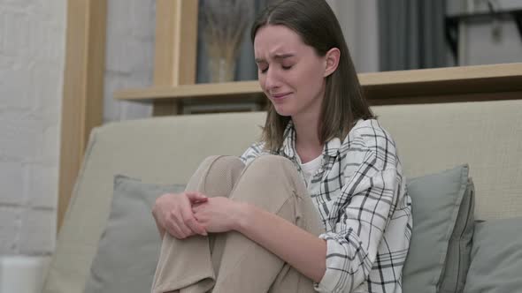 Sad Young Woman Sitting on Sofa and Crying