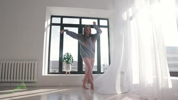 Modern Dancing  Young Woman in Blue Sweater Dances in Spacious Room By the Windows