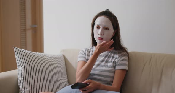 Woman apply facial mask and watch tv at home