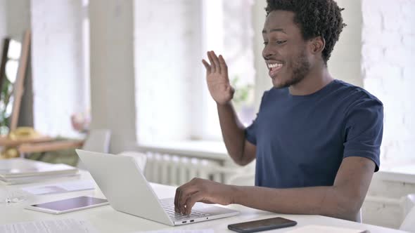 Young African Designer Doing Video Chat on Laptop