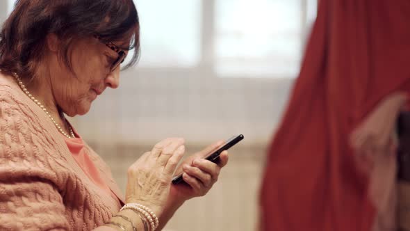 Senior Woman Using Smartphone For Social Networks And Browsing In Internet. Woman Holding Mobile.