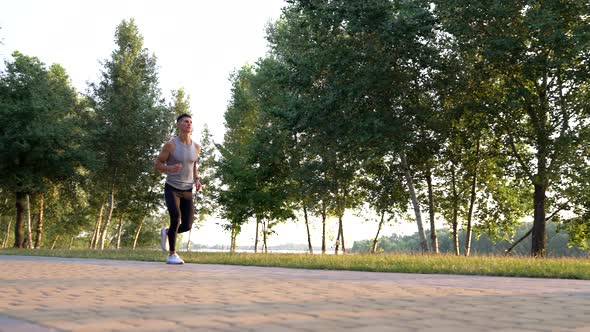Outdoor Training of Sporty Man Running in Park Jogger