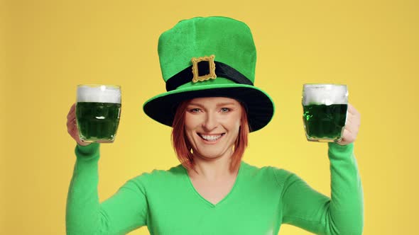 Smiling woman with leprechaun's hat holding full a beer glass