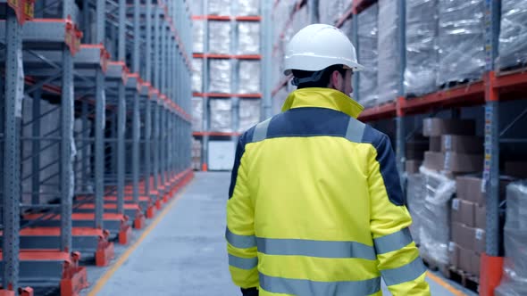 Follow footage of employees male warehouse worker engineer in hard hat working