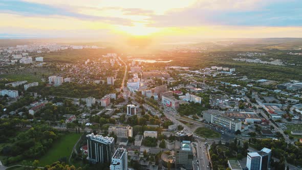 Aerial drone view of Chisinau, Moldova at sunset. Buildings, roads, greenery, cloudy sky, lake