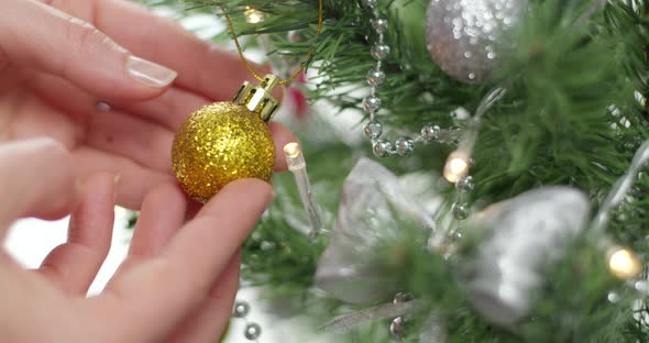 Christmas toy in hands decorating a branch of a Christmas tree