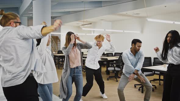 Young Group of Multiethnic Diverse Employees Smiling and Dancing Rejoicing About Developing of a New