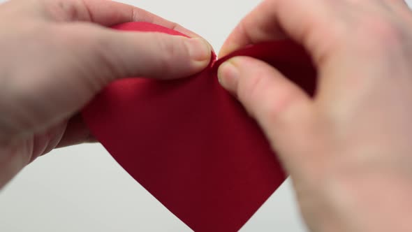 Hands Tearing Red Paper Heart on Two Half Close Up View