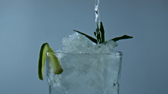 Water Pouring Iced Cocktail in Glass Closeup