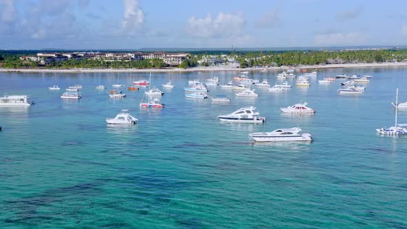 Anchored yacht boats on turquoise crystalline sea water of Dominican Republic. Aerial sideways view