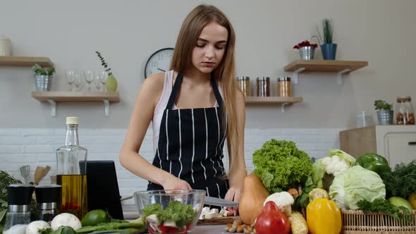 Vegan Woman Looking for Culinary Recipe Online on Digital Tablet. Cooking Salad with Raw Vegetables