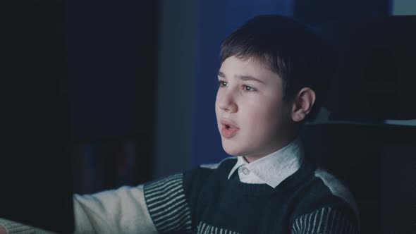 Smiling Boy Making Video Call While Sitting at Computer Laptop Late at Night