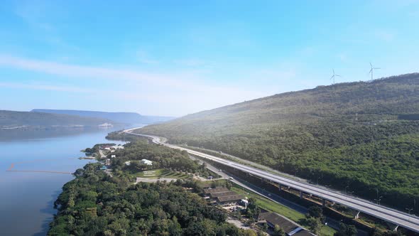 beautiful expressway in a green forest with a dam on the side of the road between mountains.