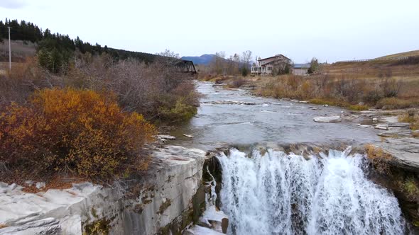 Aerial 4k slow motion fly over twin waterfalls in Alberta, Canada on a cloudy autumn day. Large amou