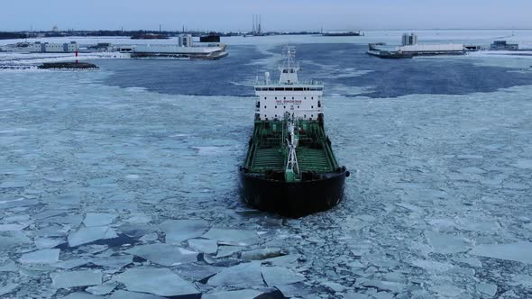 A Large Ship Sails Through the Sea in the Midst of Ice Against the Background of a Dam