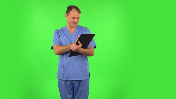 Medical Man Thinks, Speaks and Writes at Black Folder with Pensil. Green Screen